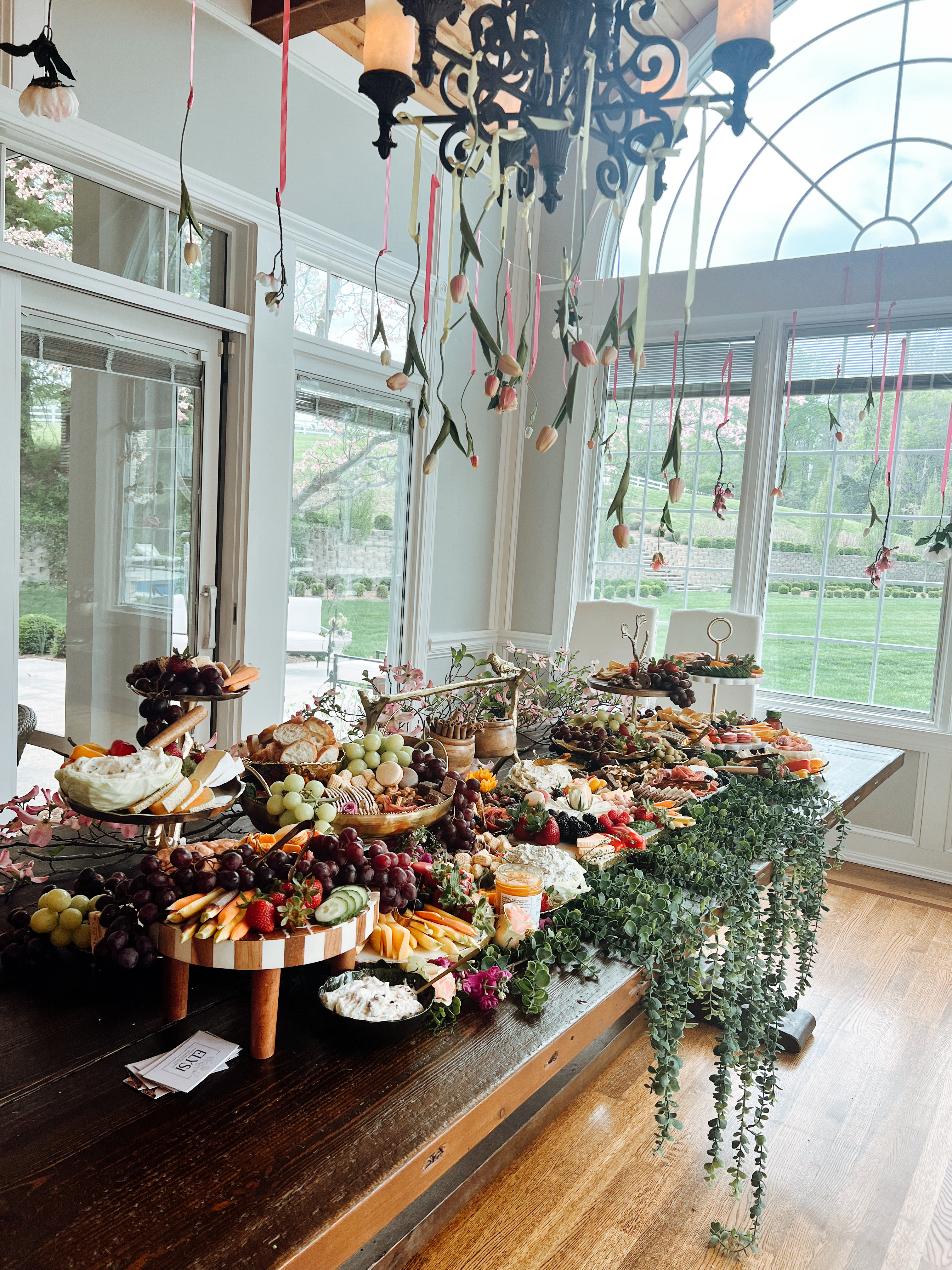 A grazing tablescape beneath a chandelier dripping with tulips on ribbons