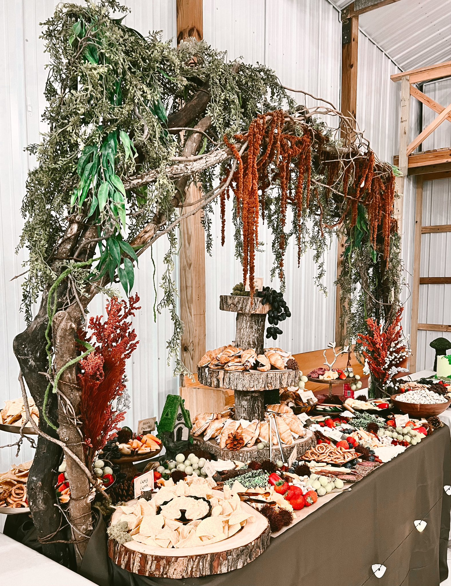 A foraged-arch grazing display under branches and dried botanicals